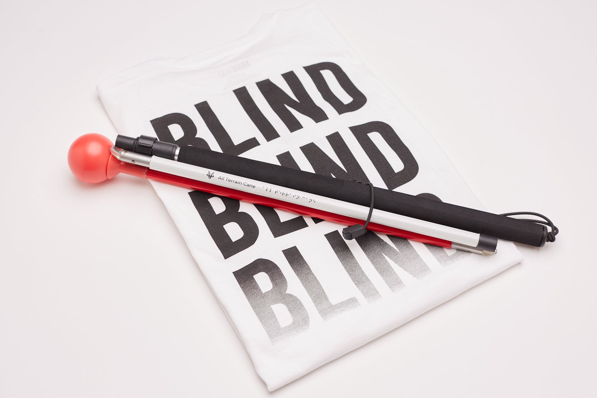 All Terrain Cane in front of a banner reading the word "Blind" three times.