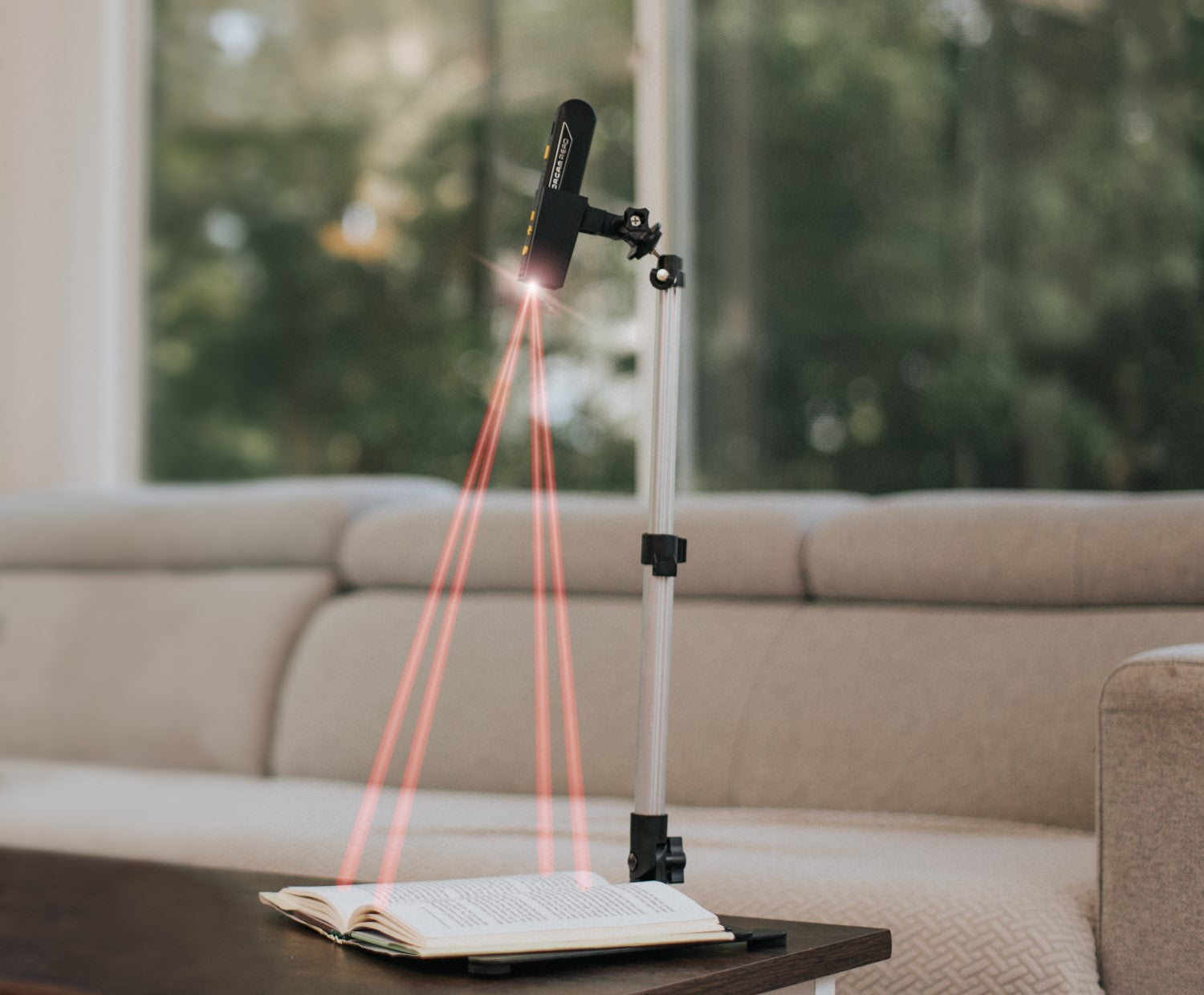 Orcam Read 3 and 5 smart reader and magnifier on its stand reading a book.