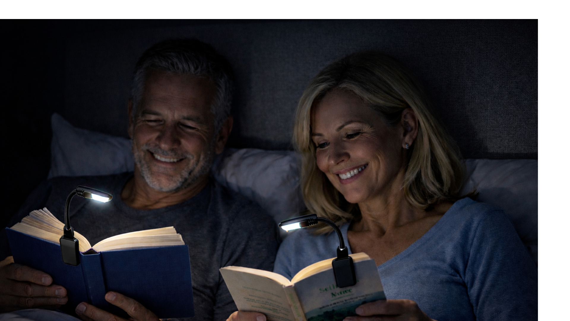 Man and woman reading in beed using book lights.