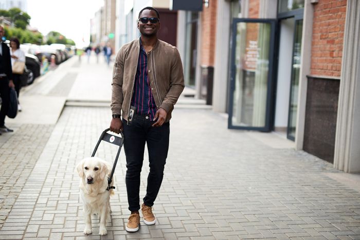 Man and his guide dog walking down the street using the StellarTrek.