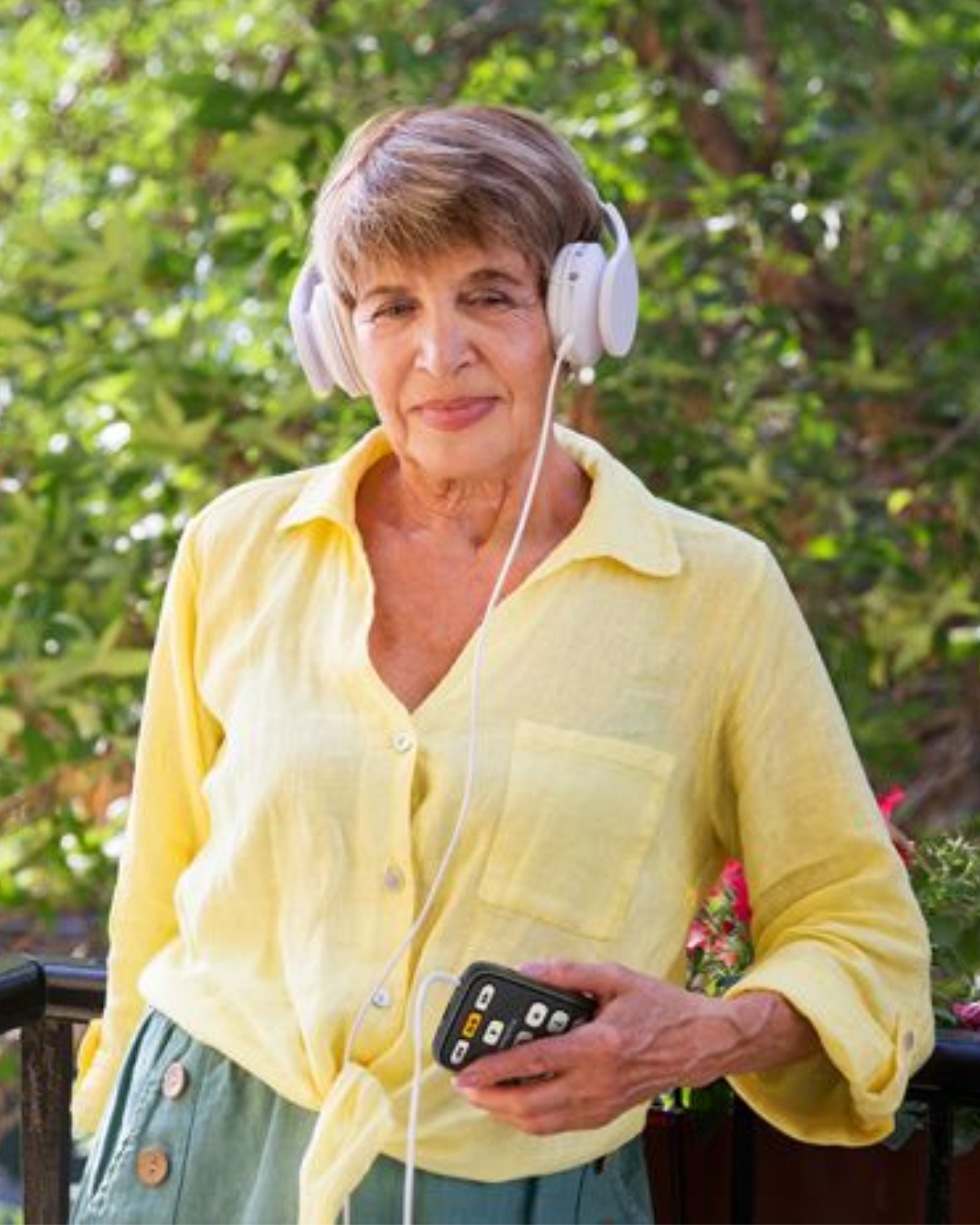 Woman walking outdoors listening to media on Victor Reader from HumanWare.