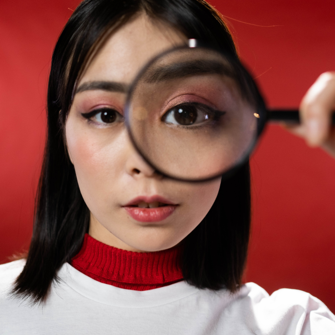 Image of a woman holding a magnifying glass in front of her left eye.